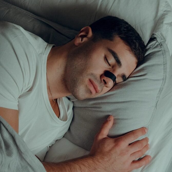 a man sleeping with a nasal strip on his face